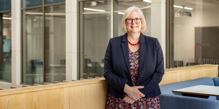 A headshot of Professor Cath Noakes, stood in the Bragg Building in 2023