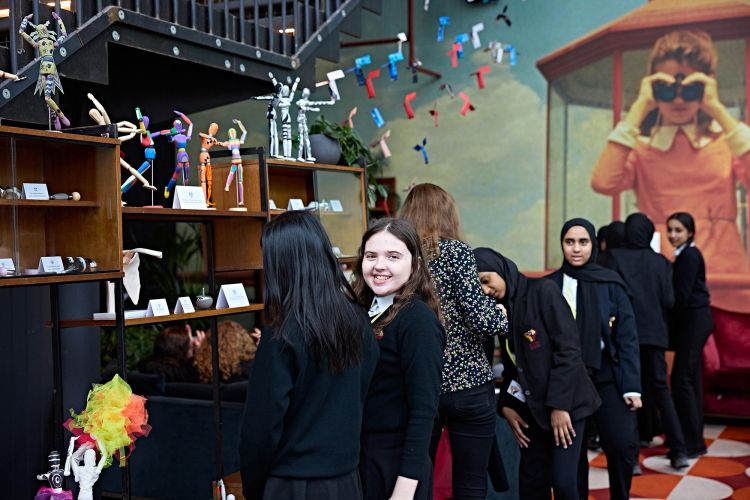 A number of school girls looking at a display of engineering items, with one girl smiling directly at the camera.