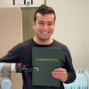 Photo of AI and Robotics PhD graduate and Research Fellow Rafael Papallas at the University of Leeds holding up his final year project.