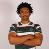 A photograph of Benjamin Matheson, a Mechanical Engineering graduate from the University of Leeds. He is stood against a grey background with his arms folded wearing a University of Leeds rugby shirt.
