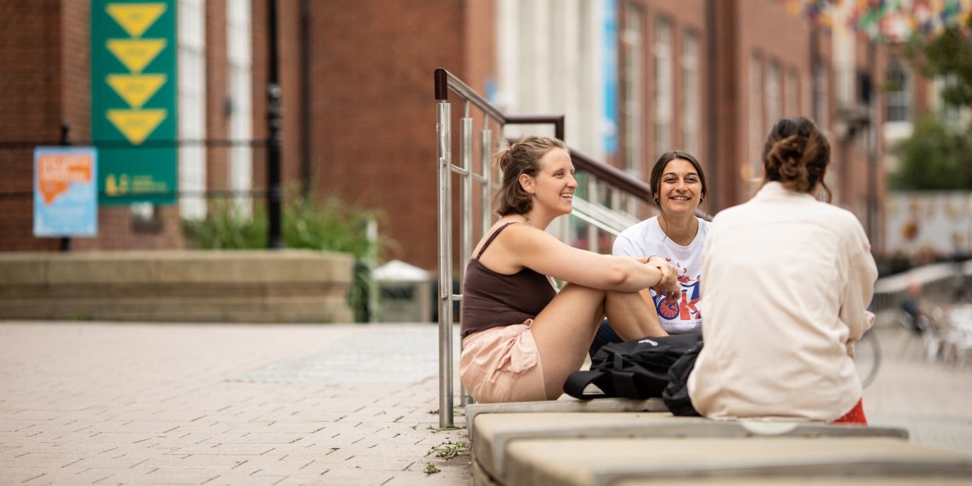 Three students sat outside the front of the Union.