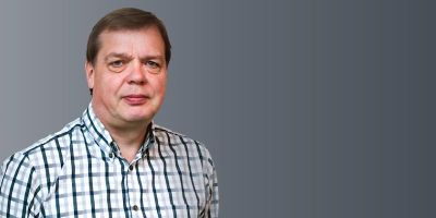 Head shot of Professor Andrew Bell in a blue and white chequered shirt.