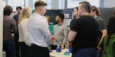 A group of students showcasing their poster to peers, staff and industry advisors.