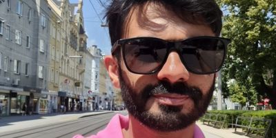 A portrait of Aitsam Hasan, wearing a pink polo shirt and sunglasses.