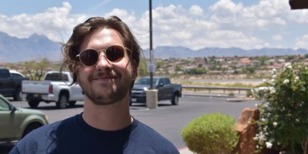 A portrait photograph of Eduards Butans wearing sunglasses stood in a carpark.