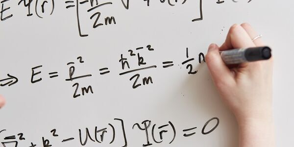 Equations written on a whiteboard, representing theoretical physics research