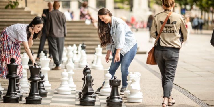 A photograph of two women playing a large game of chess.