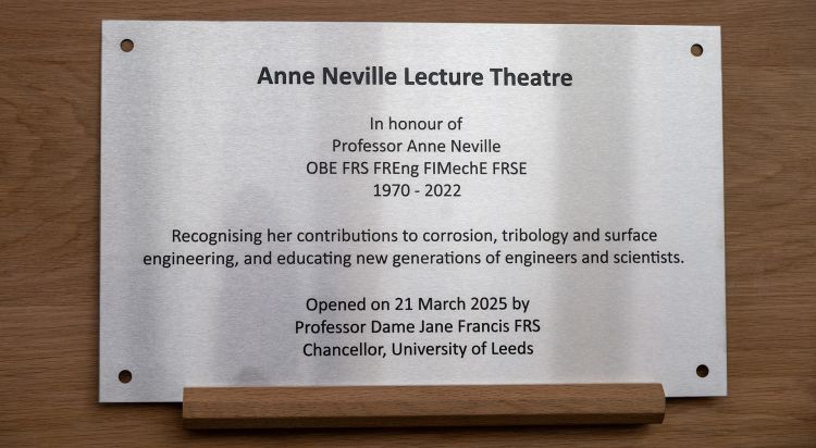 The metal dedication plaque for the Anne Neville Lecture Theatre, sitting on a wooden easel.