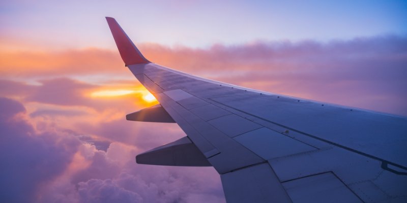An aeroplane wing pictured over clouds